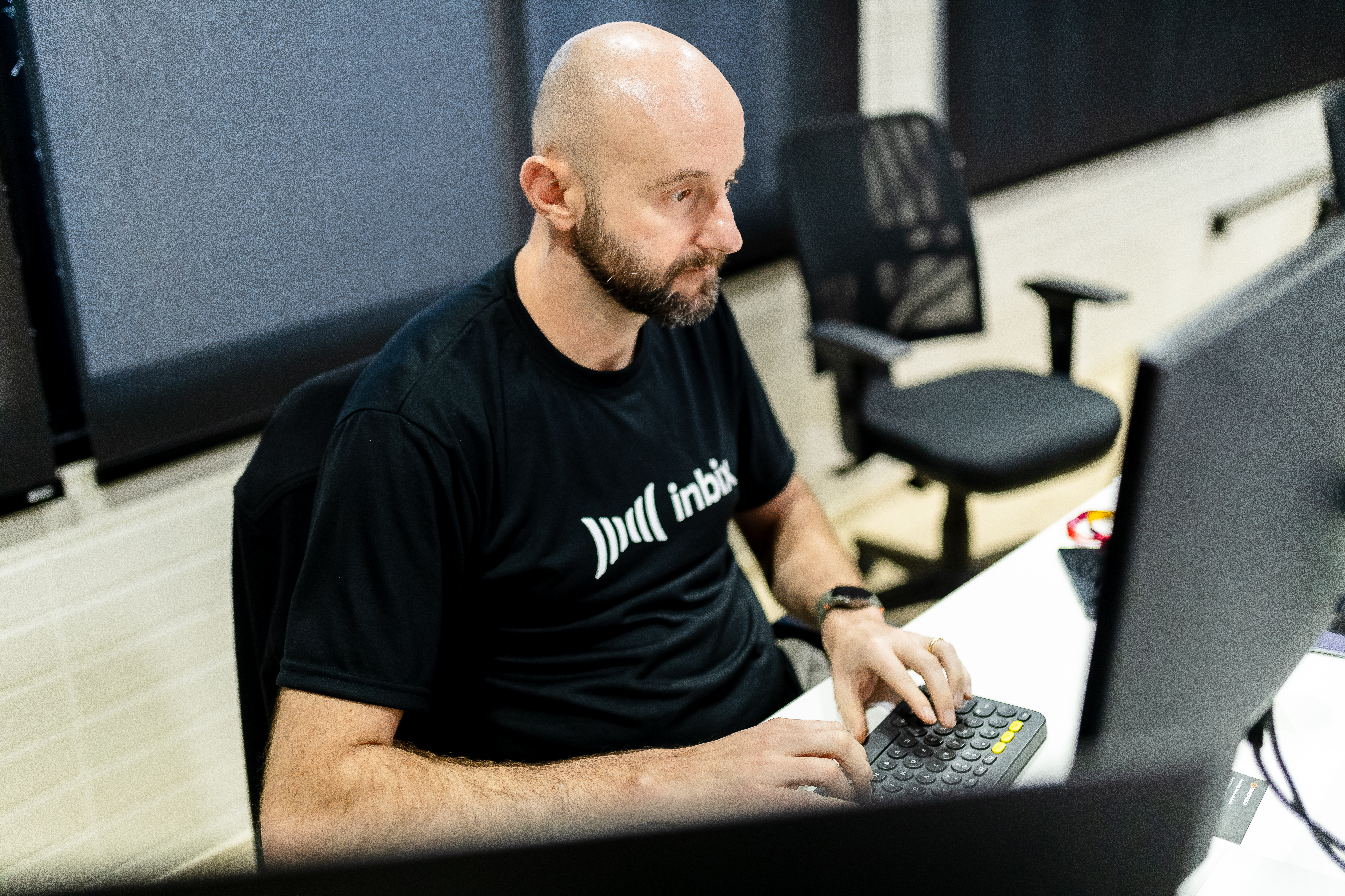 Profissional de camiseta da Inbix concentrado no trabalho ao computador