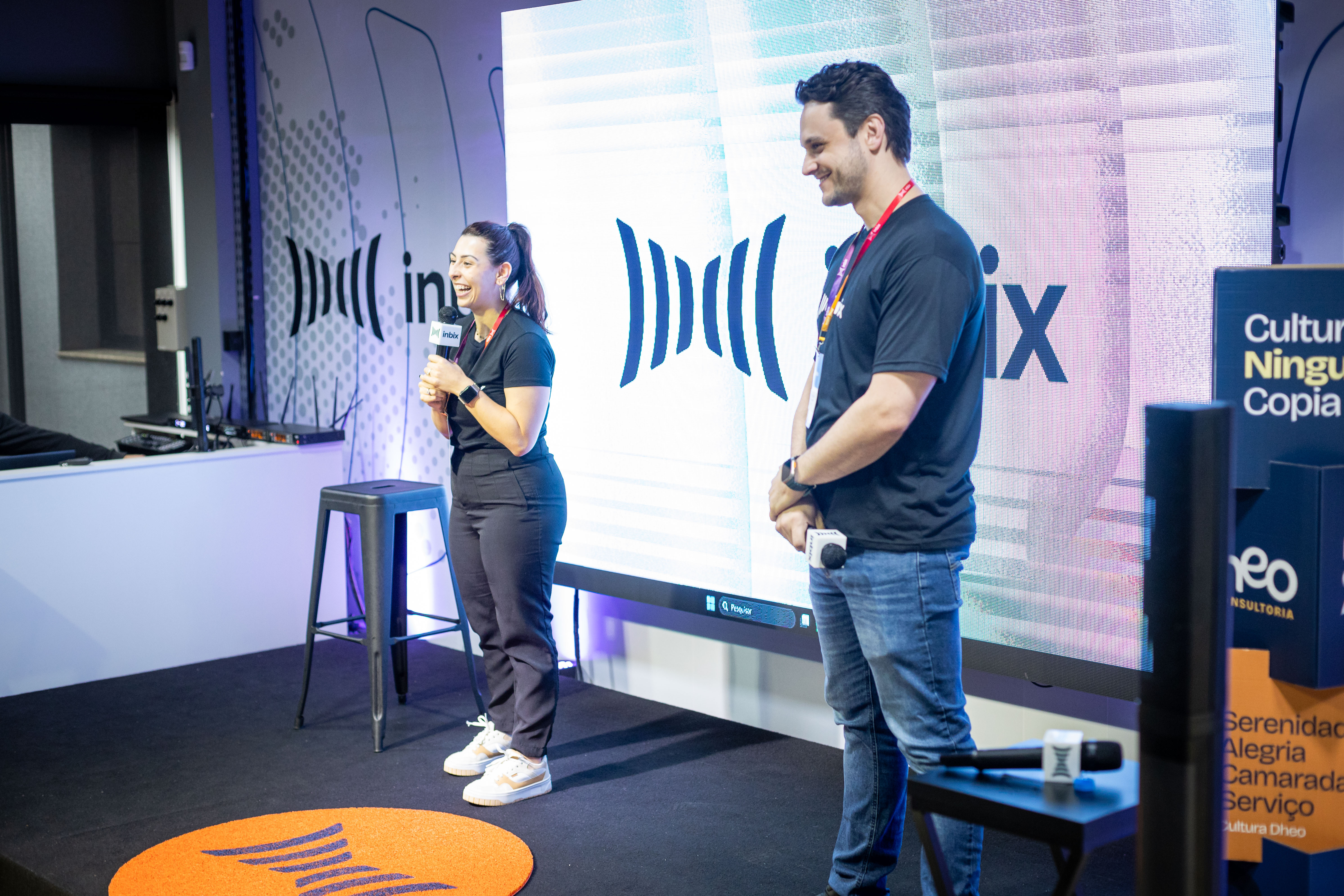 Dois palestrantes da Inbix apresentando no palco diante de um telão com a marca