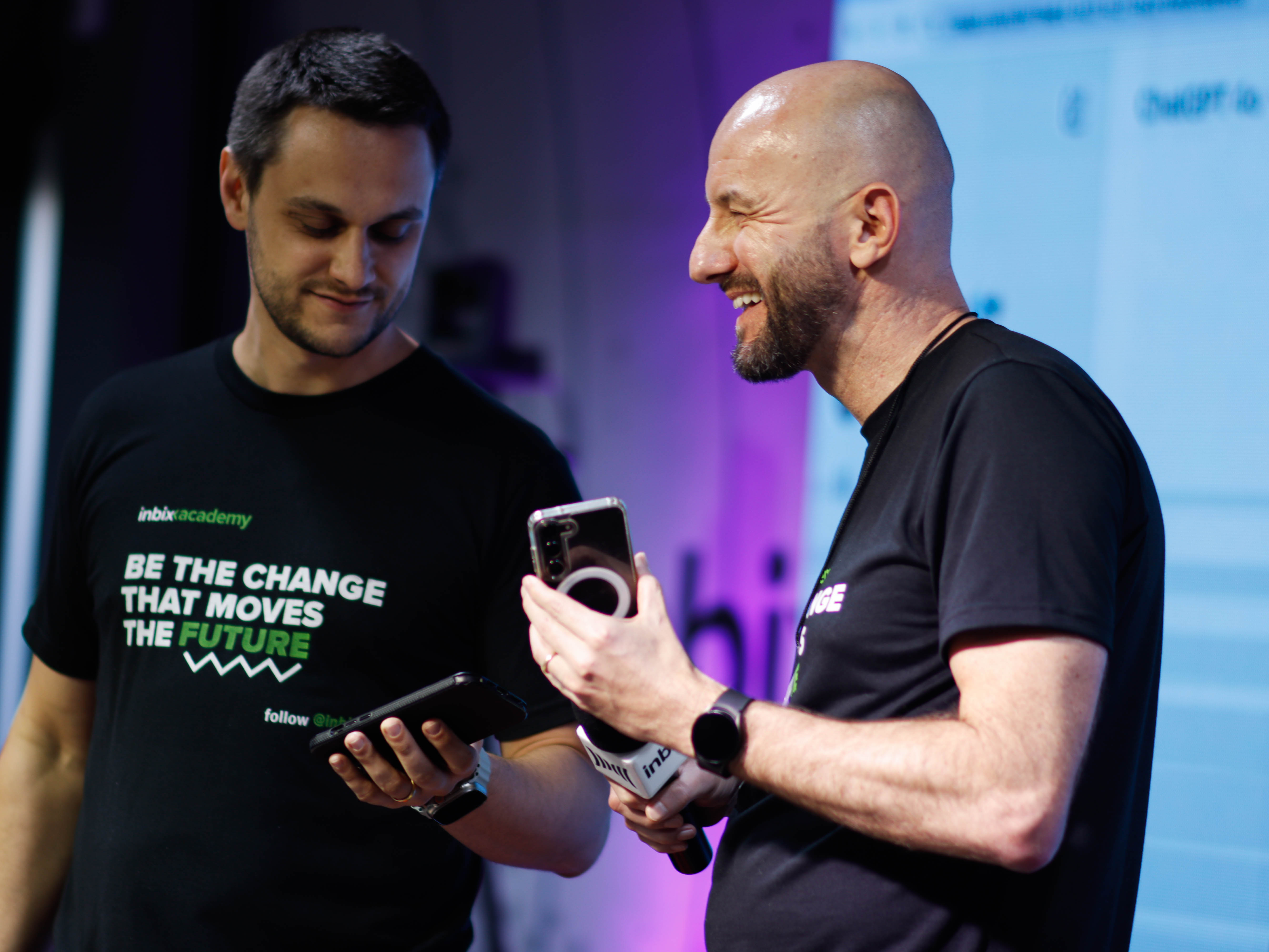Dois profissionais da Inbix conferindo o celular no palco durante um evento
