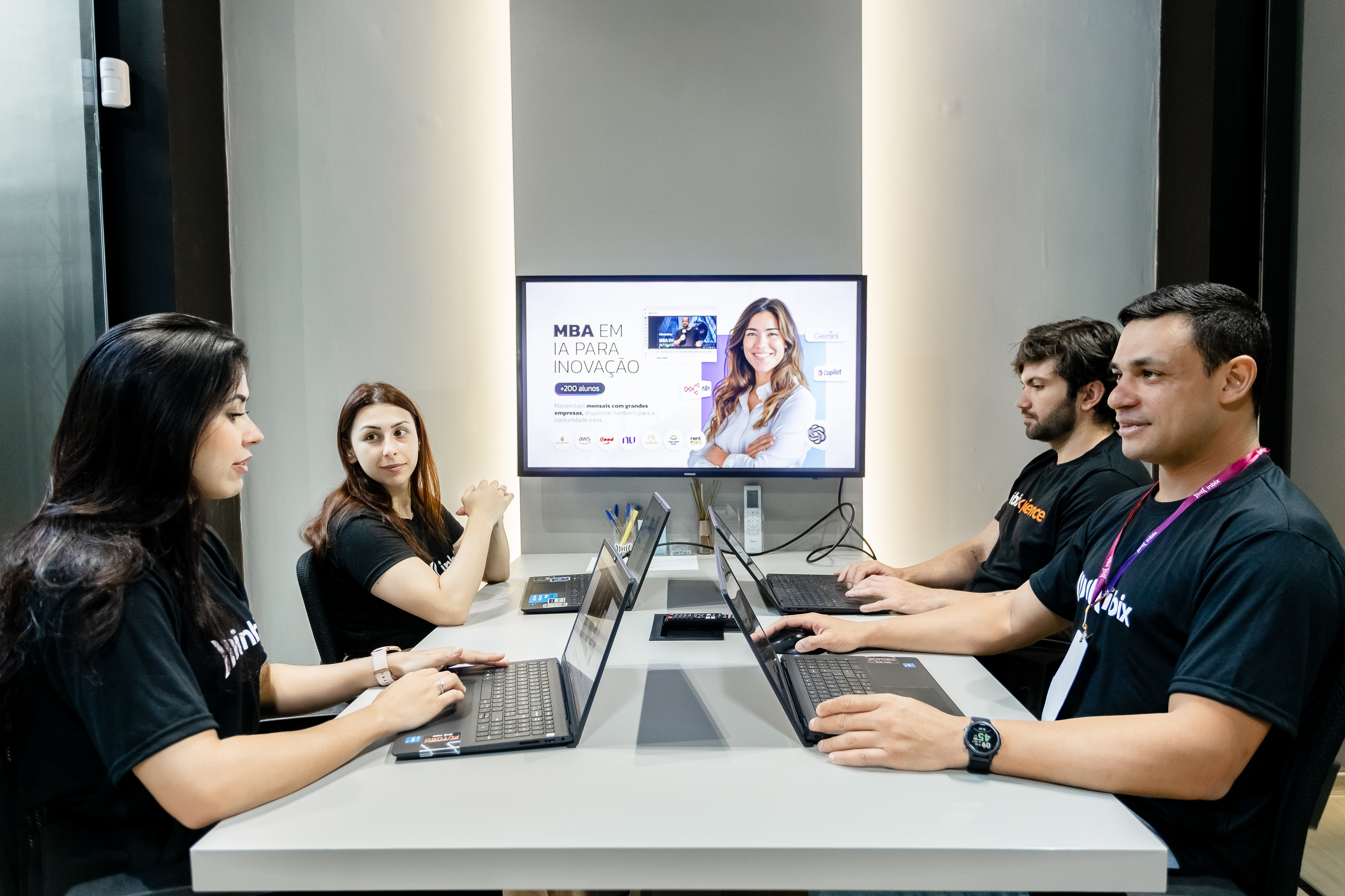 Equipe da Inbix em reunião diante do telão com a página do MBA em IA para Inovação